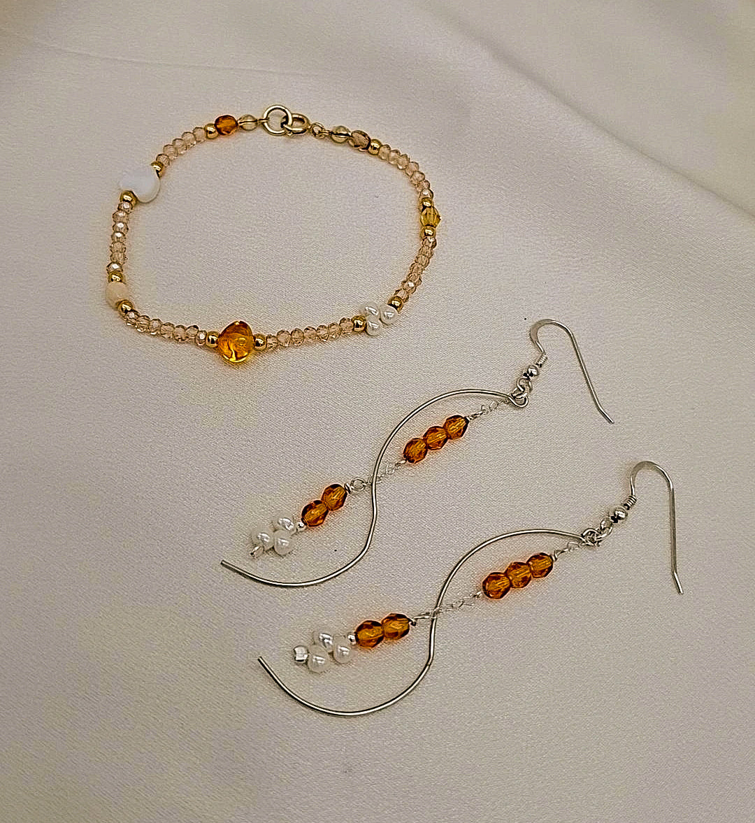 Conjunto artesanal “Destellos Dorados” con pulsera y pendientes de cristales dorados y perlas blancas, diseño minimalista hecho a mano.