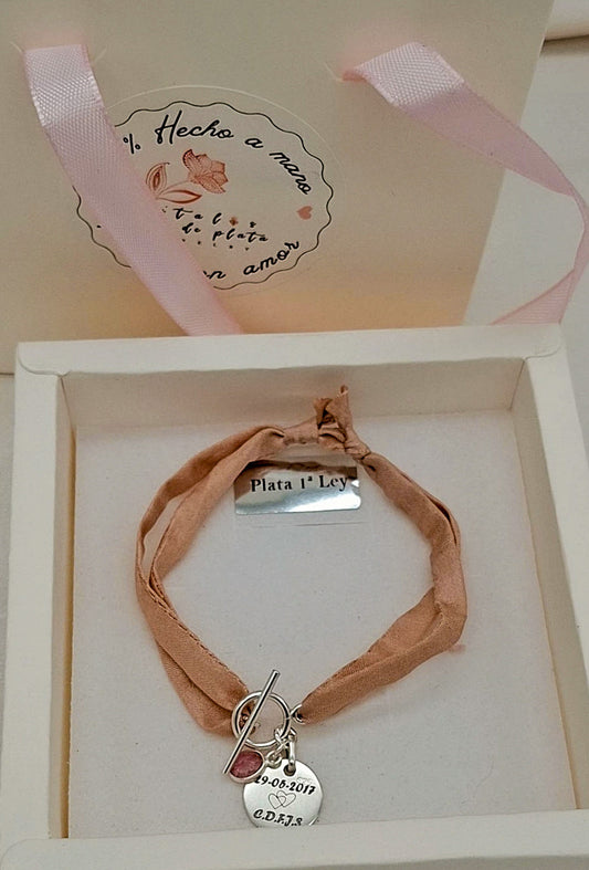 Pulsera artesanal creada con cinta de seda natural en tono nude y medalla de plata de ley 925 grabada con fecha o iniciales.